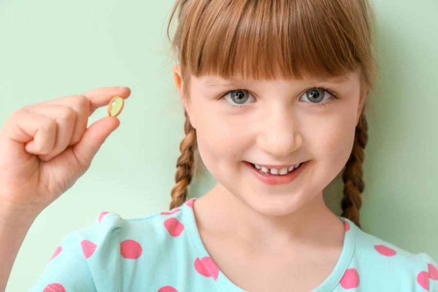 a kid holding a supplement to help boost her immunity