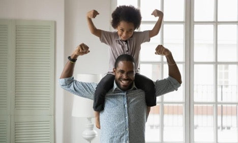 a healthy father with his son on his shoulders while both are flexing their muscles